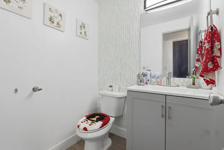 Vanity with a solid surface countertop, undermount sink, and wood-finish flooring