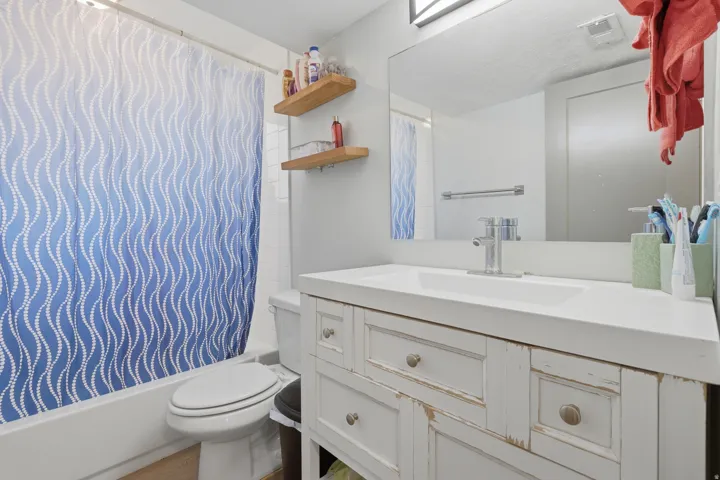 White vanity with a single basin sink, chrome faucet, and rectangular mirror