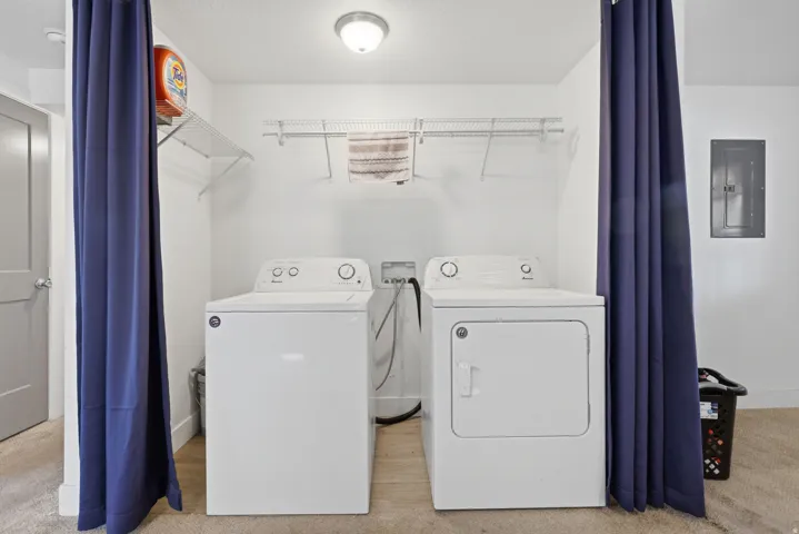 Dedicated laundry area featuring a washer and dryer, convenient overhead wire shelving, and wood-finish flooring