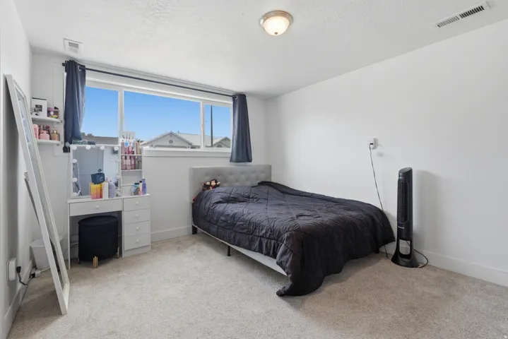 Light-toned carpeting, ample natural light from a large window, a built-in floating shelf, and a ceiling-mounted light fixture