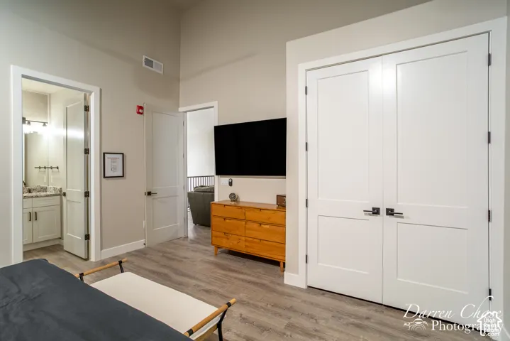 High-ceilinged room featuring wood-finish flooring, double-panel interior doors, and solid-core passage doors with matte black hardware