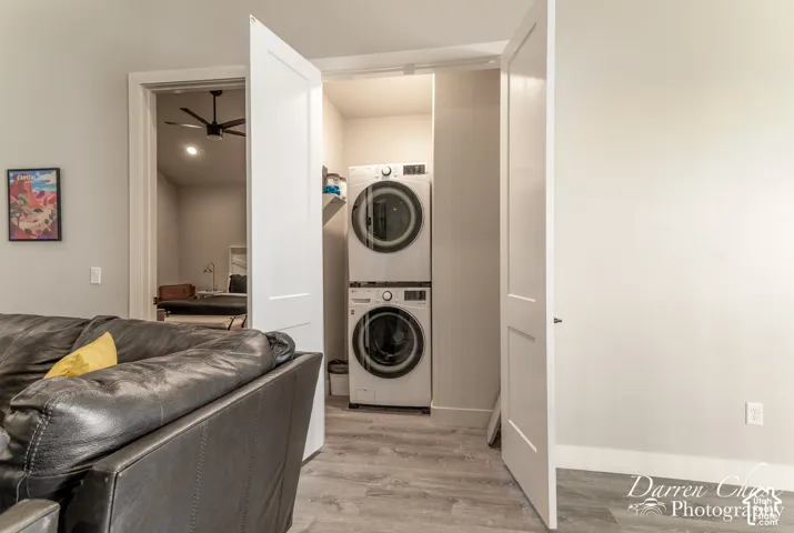 Laundry closet featuring stacked appliances and wood-finish flooring