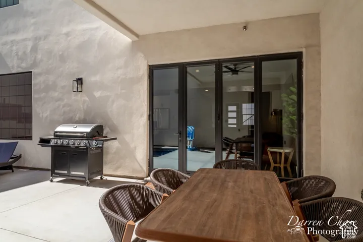 Covered patio featuring concrete flooring, textured light-toned exterior walls, and multi-panel folding glass doors