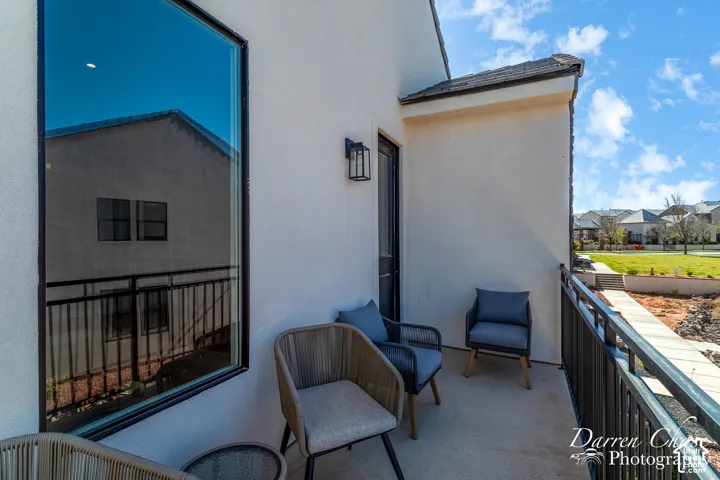 Covered balcony featuring smooth stucco exterior walls, a black metal railing, and a minimalist wall-mounted outdoor light fixture