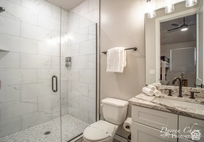 Walk-in shower with floor-to-ceiling tile, glass enclosure, and pebble-mosaic tile flooring