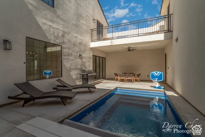 Enclosed courtyard featuring a rectangular pool, concrete decking, covered patio space, and a second-level balcony with metal railing