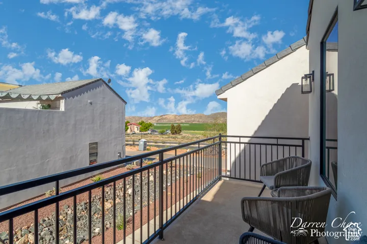 Second-story balcony featuring metal railing, neutral-toned flooring, wall-mounted exterior lighting, and mountain scenery