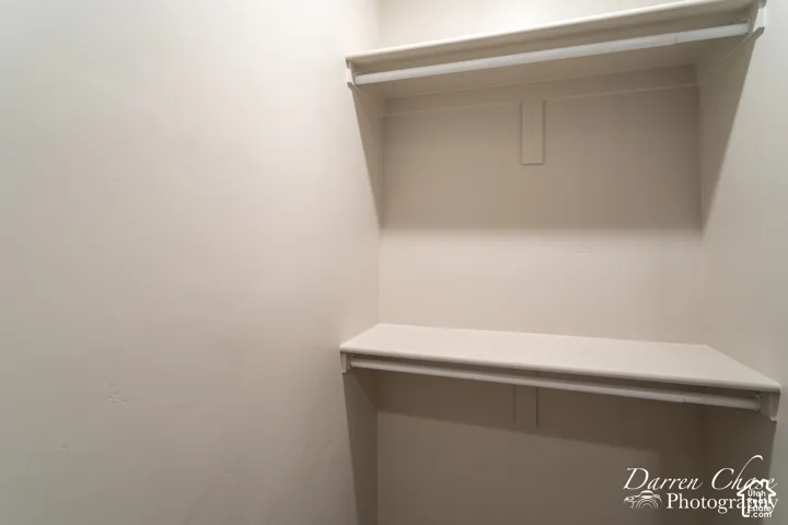 Interior storage space featuring two tiers of built-in shelving with integrated rods