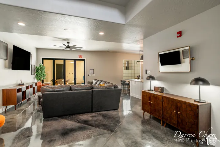 Polished concrete flooring, recessed ceiling lighting, multi-panel black-framed glass exterior doors, and a vaulted ceiling