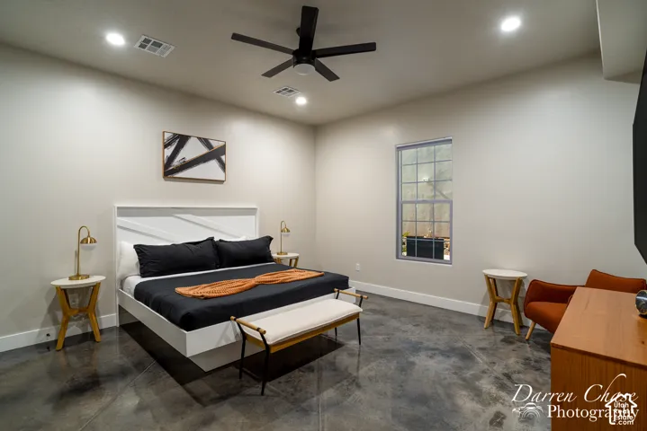 Polished concrete flooring, recessed lighting, matte black ceiling fan, and multi-pane window