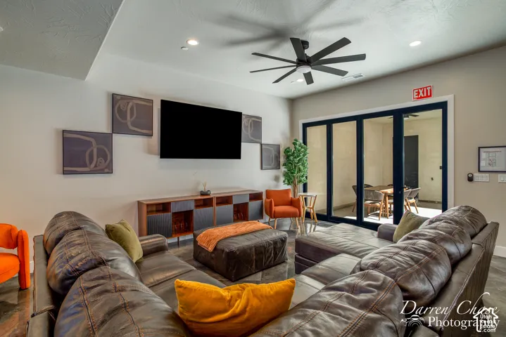 Multi-panel folding glass doors, recessed ceiling lighting, contemporary ceiling fan, and built-in low-profile cabinetry