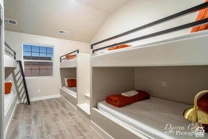 Built-in bunk bed structure featuring a smooth finish, wood-finish flooring, a vaulted ceiling, and a grid-pane window