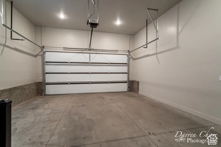 Finished garage featuring painted walls, concrete flooring, overhead lighting, and an automated sectional door