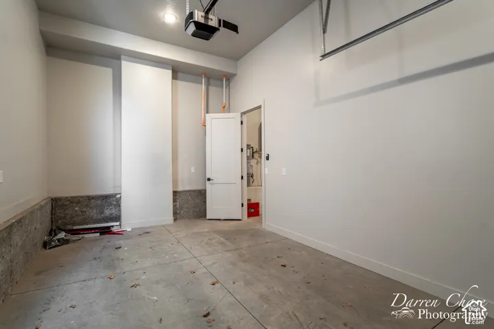 Garage interior featuring high ceilings, neutral-painted walls, concrete flooring, and an integrated garage door opener