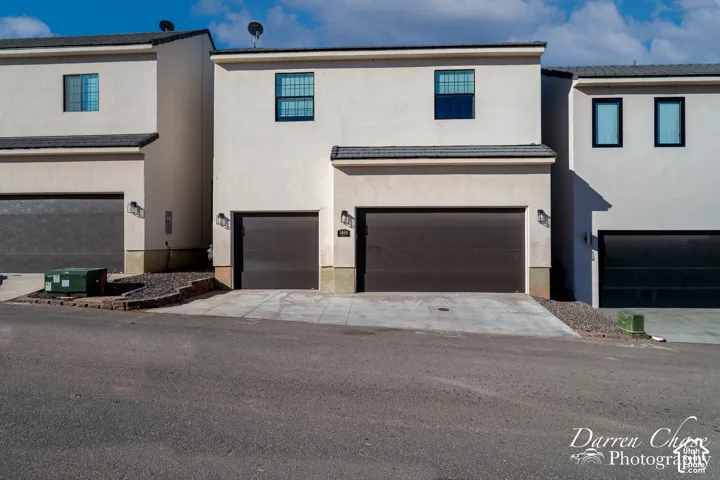 Two-story stucco exterior featuring a multi-car garage, concrete driveway, and low-profile roofline