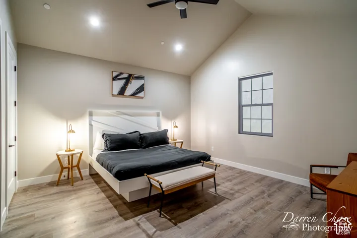 Vaulted ceiling featuring a central flush-mount ceiling fan, recessed lighting, and wood-finish flooring