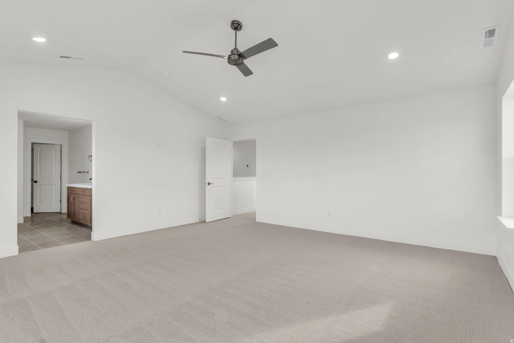 Spacious primary living area featuring neutral wall finishes, recessed ceiling lighting, and a modern ceiling fan