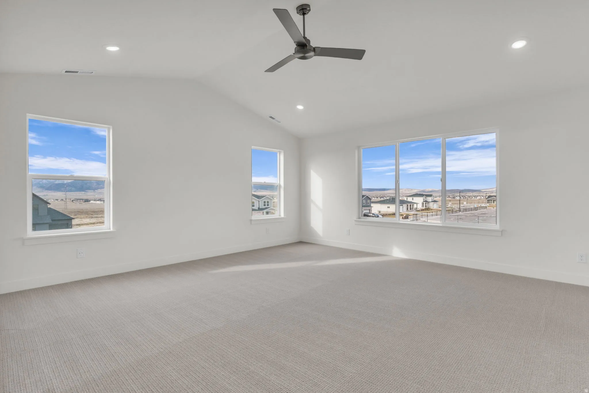Bright corner room flooded with natural light through multiple expansive windows showcasing panoramic landscape vistas