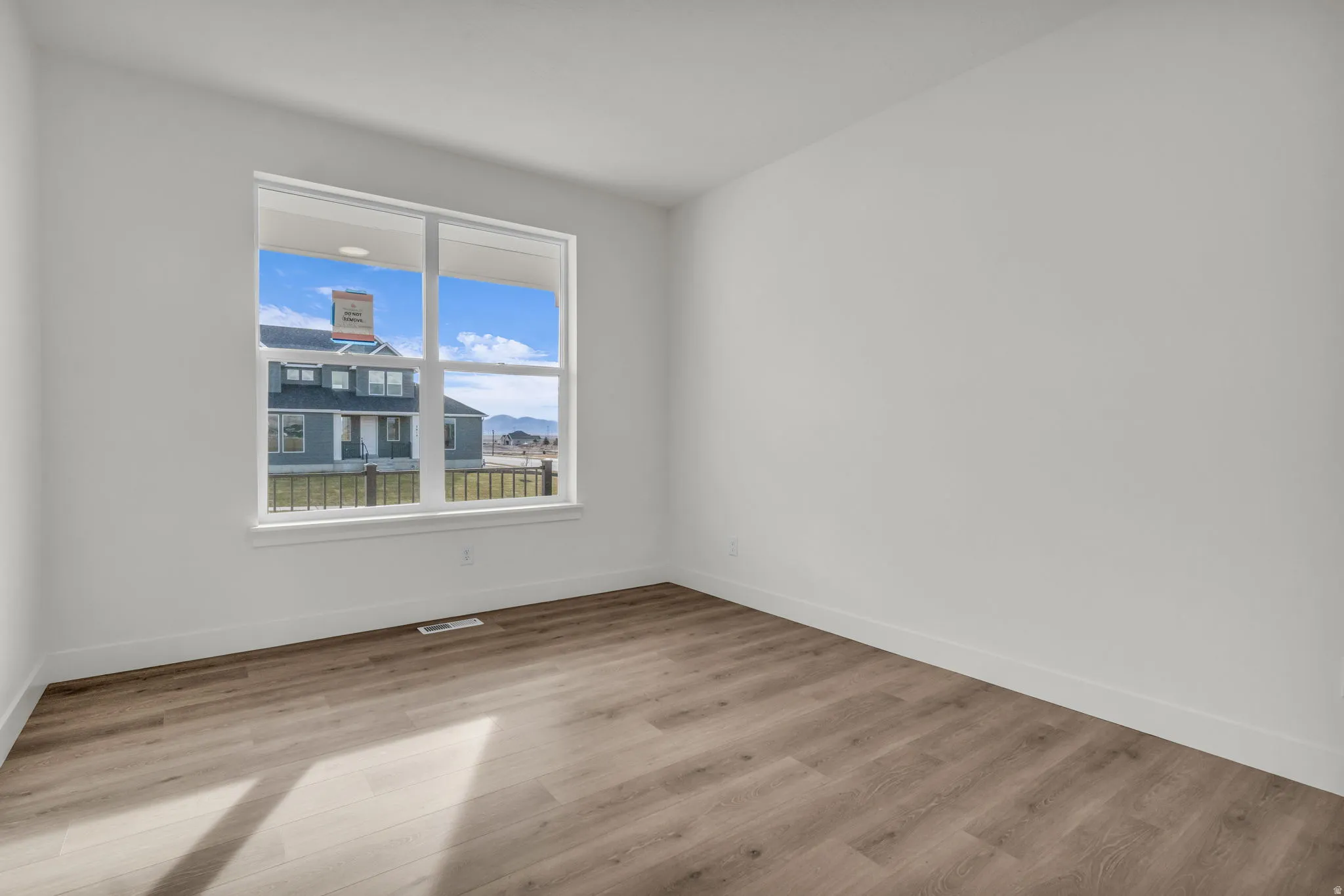 Wood-finish flooring, white painted walls, and a large window with white trim