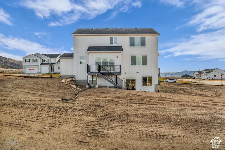 Modern farmhouse-style residence featuring a clean white exterior with multiple levels, black-trimmed windows, and a covered entry deck with metal railings