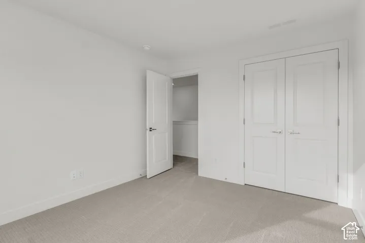 Neutral-toned carpeting, white walls, and a white paneled door with black hardware
