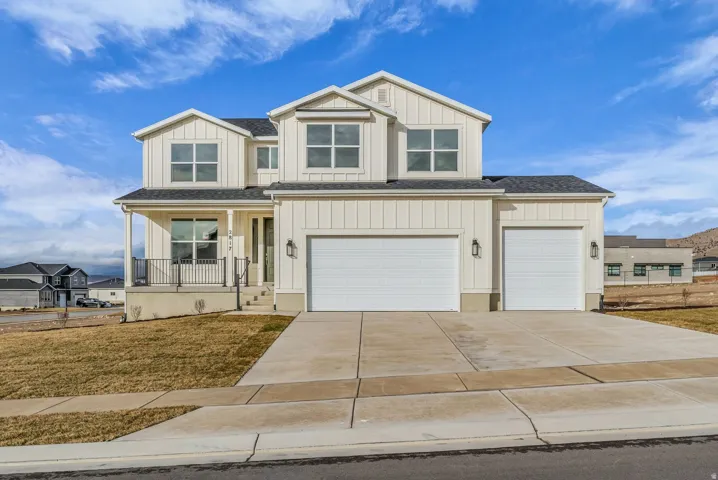 Farmhouse two-story home featuring a striking gabled roofline with large covered porch, an expansive front-load three-car garage with RV sized garage door in third bay.