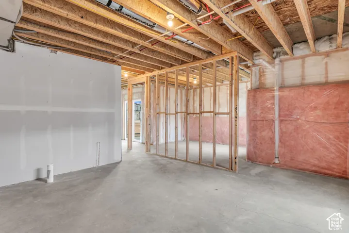 Unfinished interior space with exposed ceiling joists, framed wall structures, installed insulation, and a concrete floor