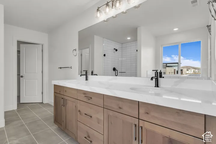 Spa-inspired primary bathroom featuring an expansive dual-sink vanity with wood-finish cabinetry, white quartz countertops, and matte black hardware