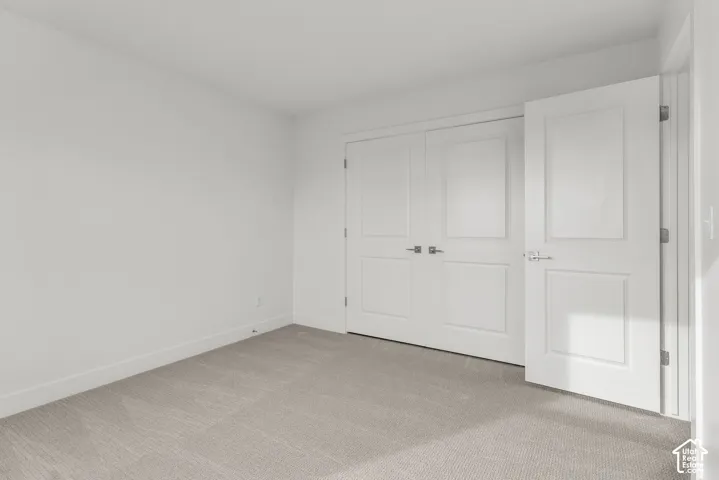 Bright, light-filled bedroom featuring pristine white panel doors with polished hardware, neutral wall finishes, and soft gray carpet flooring throughout
