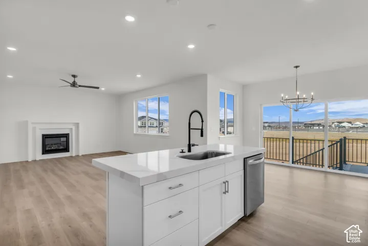 Open-concept kitchen and living area featuring a large white island with waterfall-edge countertop, stainless steel appliances, and a professional pull-down faucet