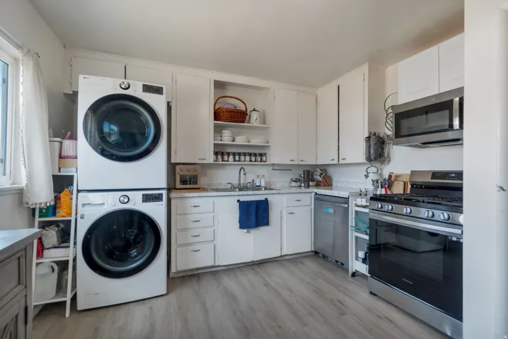 White cabinetry with stainless steel appliances, including a built-in microwave and gas range