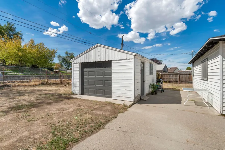 Detached garage with a paneled garage door, adjacent to a paved concrete area