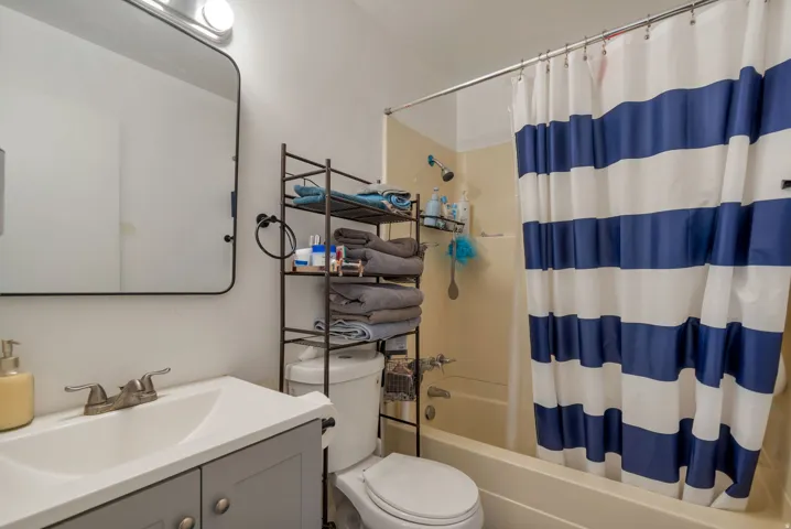 Vanity with an integrated sink and brushed nickel faucet, a rounded rectangular mirror, and a built-in shower/tub combination