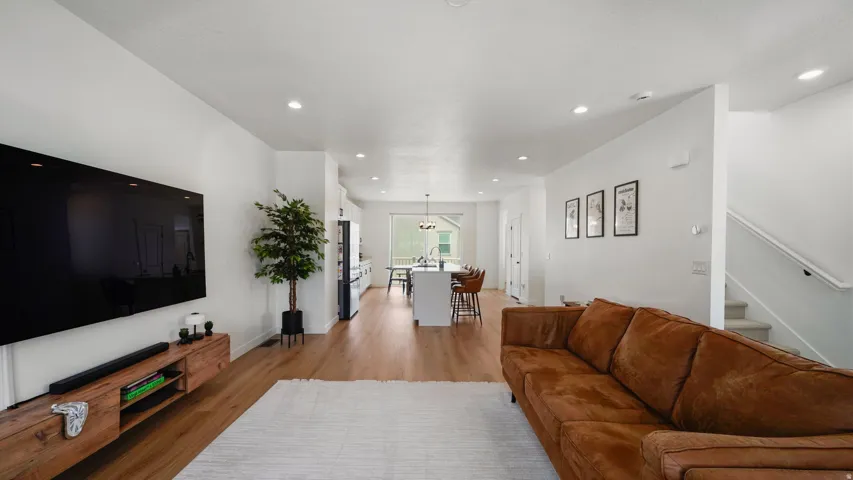 Open-concept living area with wood-finish flooring, recessed lighting, and a white color palette