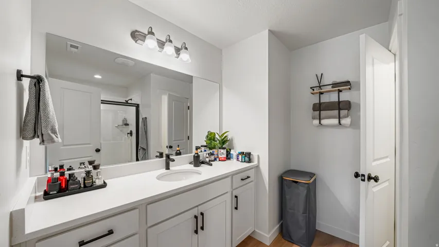 Extended vanity with a white countertop and integrated sink, mirrored wall, and overhead light fixture