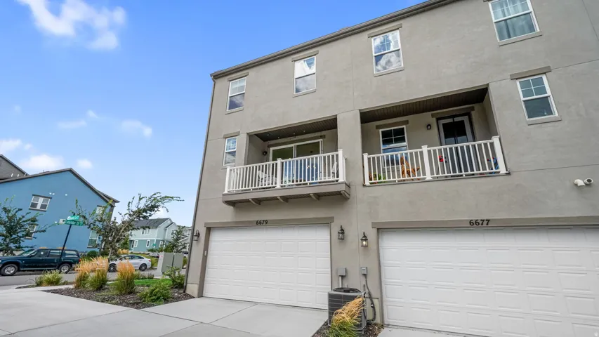 Stucco exterior with multiple windows, individual garages, and two balconies with white railings