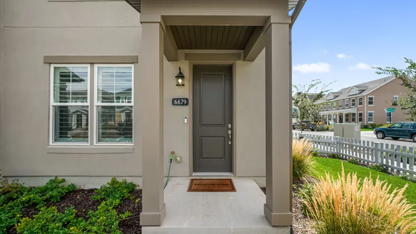 Covered front entry with substantial support columns, a paneled door, and an exterior light fixture