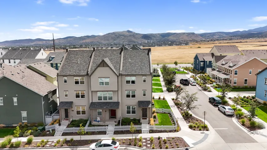 Townhome exterior featuring gabled roofs, a partial white picket fence, and landscaped front yards