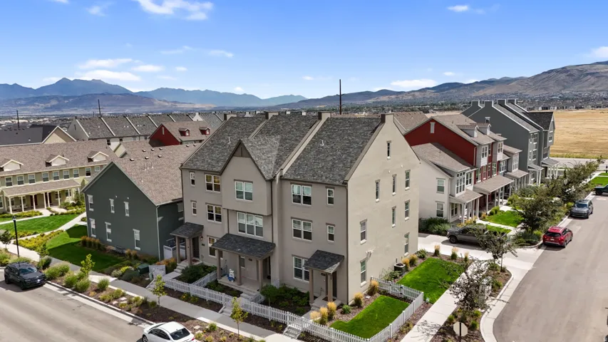Townhome exterior with a pitched shingle roof, light-colored stucco facade, and covered front porch