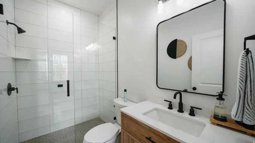 Walk-in shower with clear glass enclosure and white tile surround