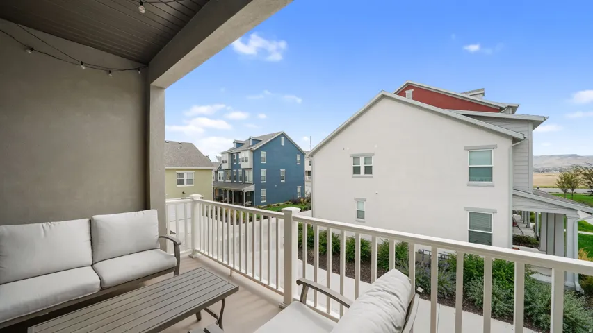 Covered balcony featuring a slatted ceiling, textured exterior wall, and white railing