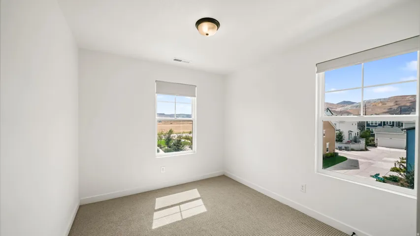 Bright room with two windows, neutral wall finishes, and carpeted flooring