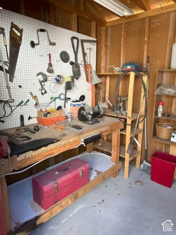 Workshop space featuring a wooden workbench, wall-mounted pegboard organization system, and integrated wooden shelving