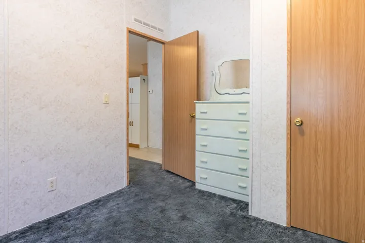 2nd bedroom with old blue carpet.  Textured wall finishes and wood-finish doors, complemented by dark carpet flooring