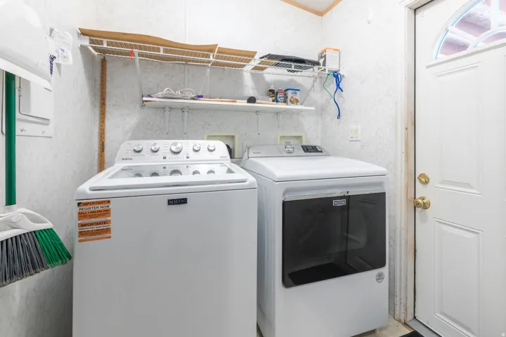 Laundry area featuring a side-by-side washer and dryer, wire shelving, and a paneled entry door with an arched transom window