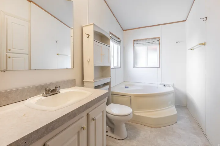 Primary Bath with Separate Shower, Garden Tub. Vanity with integral sink, mirrored wall, built-in wall cabinet, additional wall shelving, and corner tub with surrounding windows