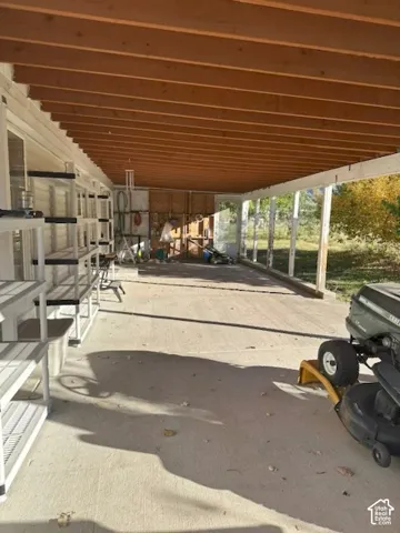 Covered patio featuring an exposed-beam wood ceiling, concrete flooring, and support pillars