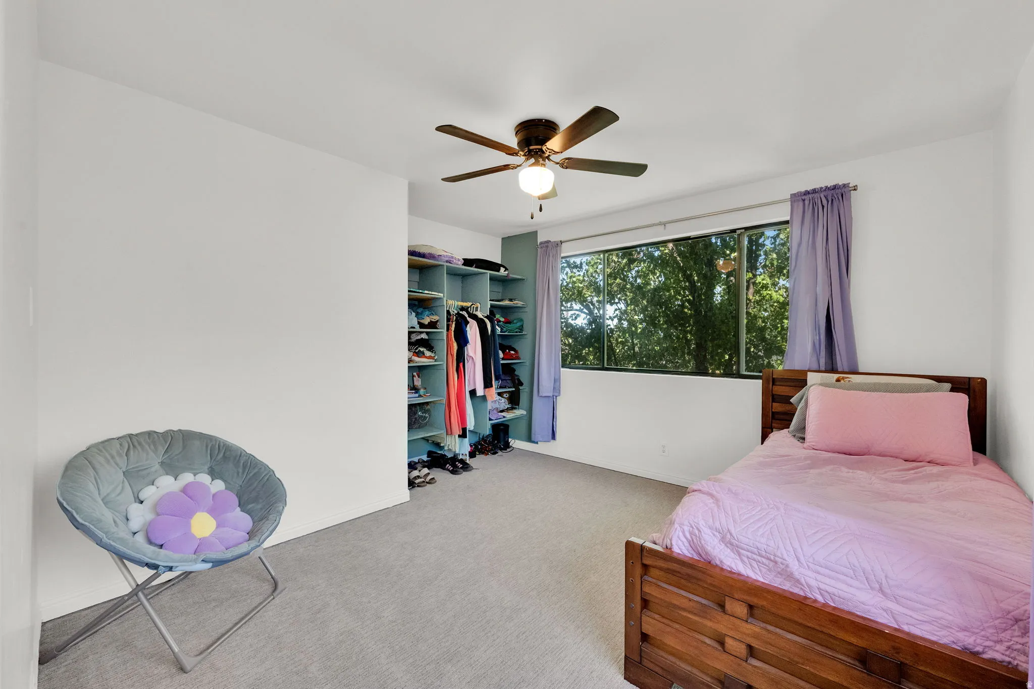 Wall-to-wall carpeting, ceiling fan with integrated lighting, built-in shelving, and large window