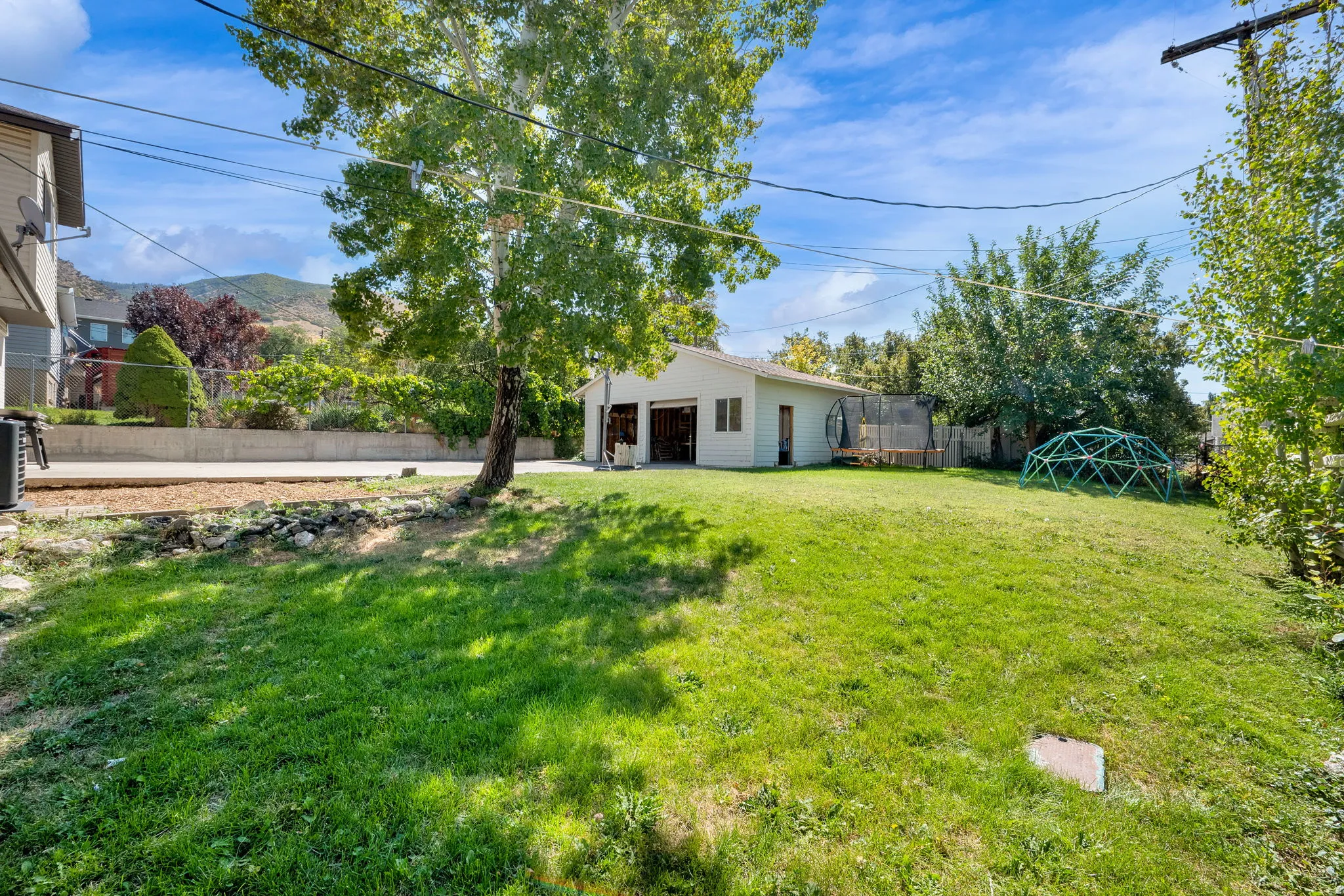 Expansive green lawn with mature trees and a detached structure
