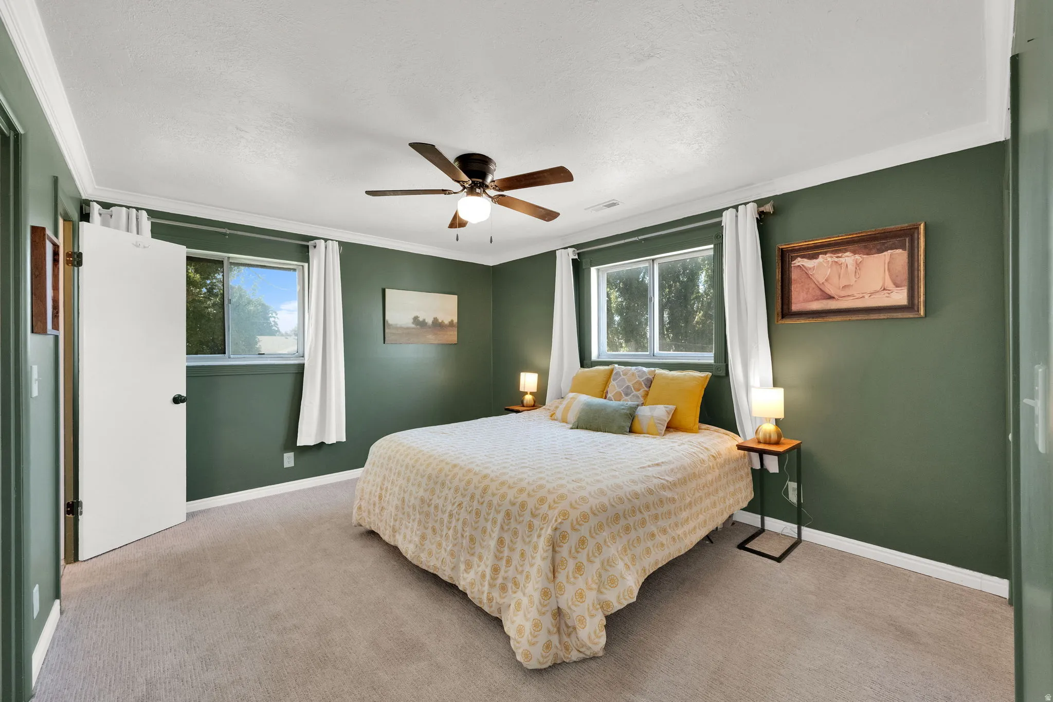 Carpeted room featuring multiple windows, a ceiling fan with integrated lighting, and crown molding